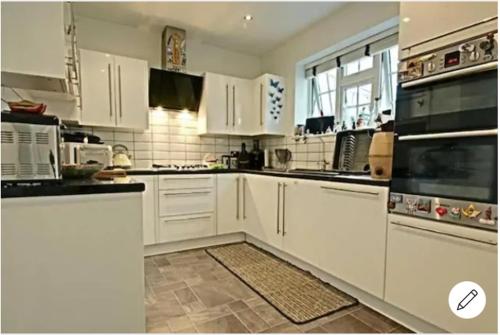 a white kitchen with white cabinets and appliances at Amit's adobe in London