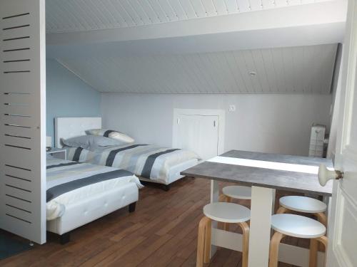1 dormitorio con 2 camas, mesa y taburetes en Chambres d'Hôtes Selon Morphee, en Selongey