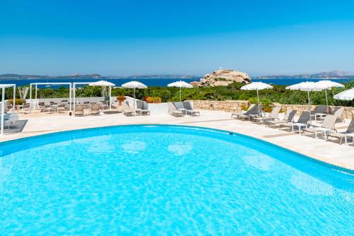 a large swimming pool with chairs and umbrellas at Hotel Grand Relais Dei Nuraghi in Baja Sardinia