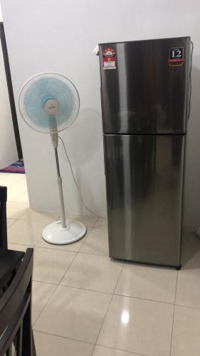 a fan sitting next to a refrigerator in a kitchen at Hasnifana Homestay Seri Iskandar in Seri Iskandar