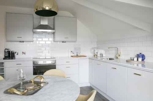 a kitchen with white cabinets and a table and chairs at Sanderson Suites in Harrogate