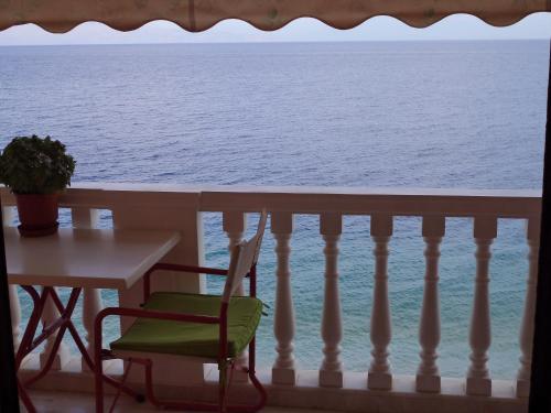 a table and chair on a balcony looking out at the ocean at Antonios Rooms in Akrata