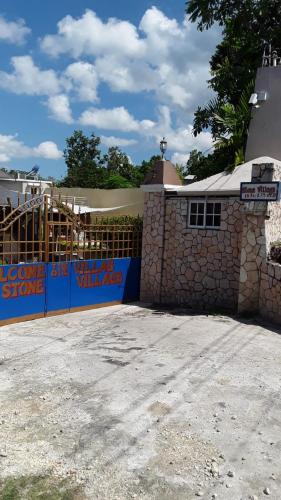 a building with a fence and a stone wall at Boutique B&B at Stone Village in Bluefields
