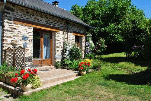 a stone house with a porch and flowers in front of it at Gîte le pré des Colombes in Troche