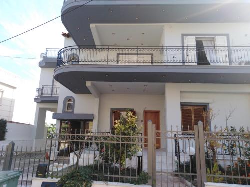 a white house with a balcony on top of it at Dora's Apartment 5 min from airport in Spata