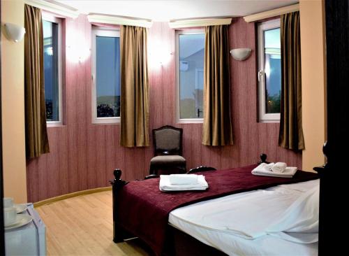 a bedroom with a bed and a chair and windows at Twins Hotel in Tbilisi City