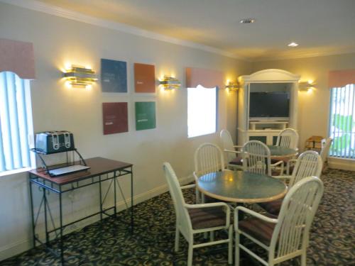 a room with a table and chairs and a television at Fairview Inn & Suites Mobile in Mobile