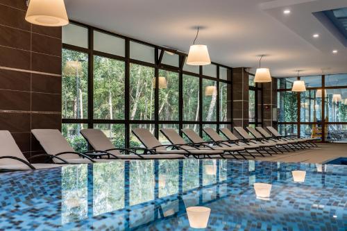 a room with a pool with chairs and windows at Gradiali Wellness and SPA in Palanga