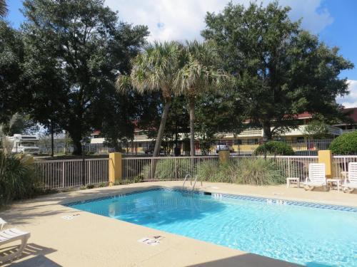 a swimming pool in a yard with chairs and trees at Fairview Inn & Suites Mobile in Mobile