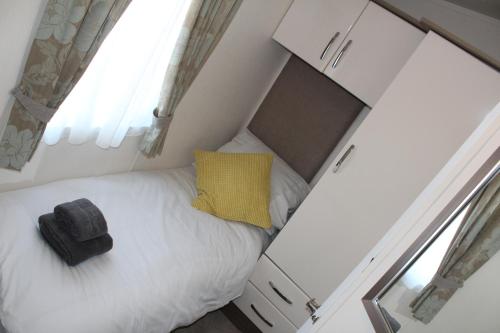 a small bed in a small room with a yellow pillow at Moonlight Ridge -2 bedroom lodge with hot tub in Felton