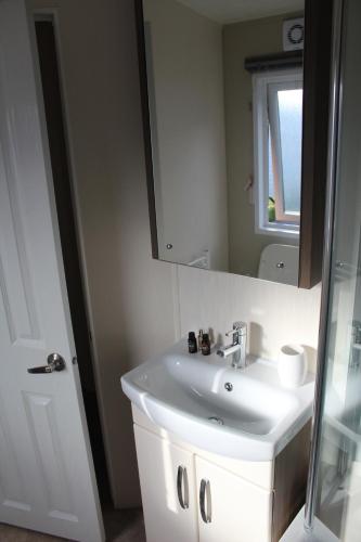 a bathroom with a white sink and a mirror at Moonlight Ridge -2 bedroom lodge with hot tub in Felton