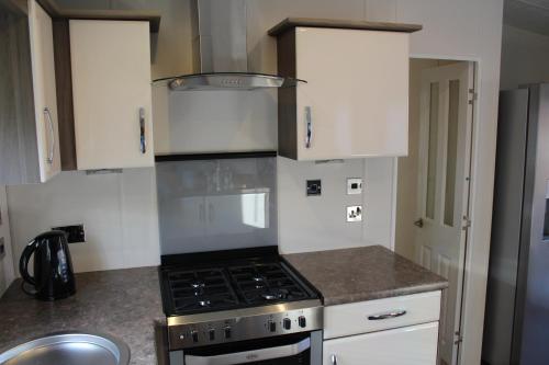 a kitchen with a stove and white cabinets at Moonlight Ridge -2 bedroom lodge with hot tub in Felton