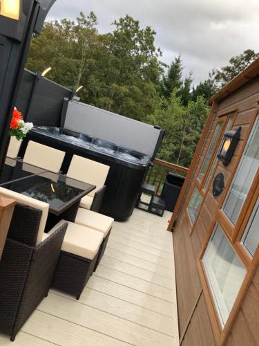 a balcony with a table and chairs on a deck at Moonlight Ridge -2 bedroom lodge with hot tub in Felton