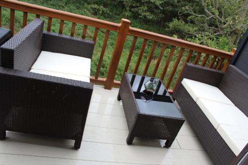 two wicker chairs and a table on a deck at Moonlight Ridge -2 bedroom lodge with hot tub in Felton