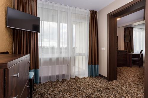 a hotel room with a television and a window at Gradiali Wellness and SPA in Palanga