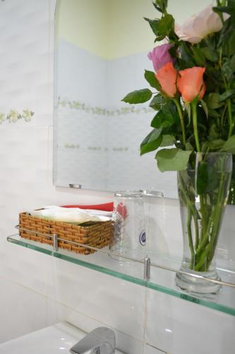 a glass shelf with a vase of flowers and a mirror at Big Home Dalat in Da Lat