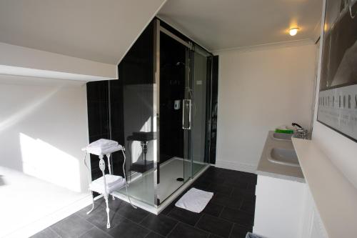 a bathroom with a glass shower and a white stool at Fines Bayliwick Hotel in Bracknell