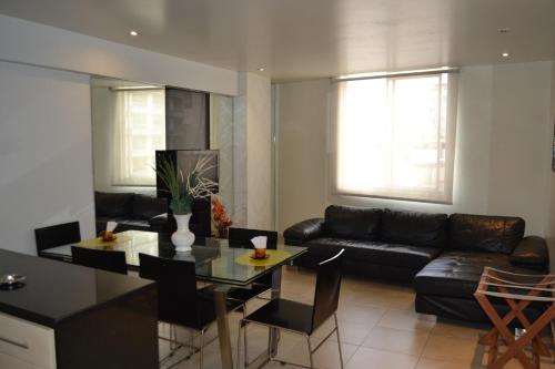 sala de estar con sofá negro y mesa en Suite Service Apart Hotel, en Lima