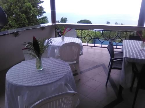 two tables and chairs with white table cloths on a balcony at Boutique B&B at Stone Village in Bluefields