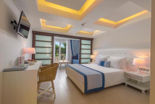 a bedroom with a bed and a desk and a television at Elinotel Apolamare Hotel in Hanioti