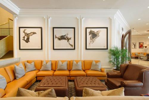 a living room with an orange couch and pictures of horses on the wall at Garden City Hotel in Garden City