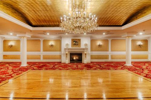 an empty ballroom with a chandelier and a fireplace at Garden City Hotel in Garden City