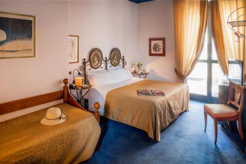 a bedroom with two beds and a hat on a chair at Hotel Palio in Asti