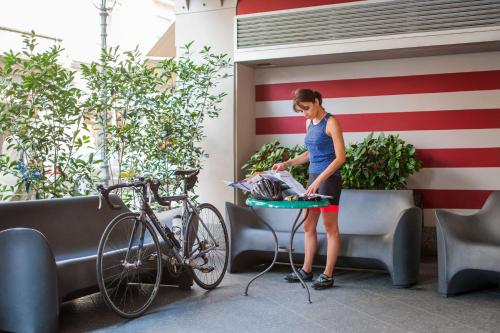 a woman standing next to a table next to a bike at Phi Hotel Palio in Asti
