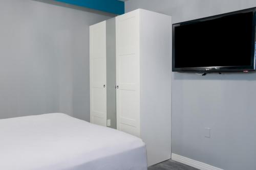 a white room with a bed and a flat screen tv at Tilbury Inn in Glendale