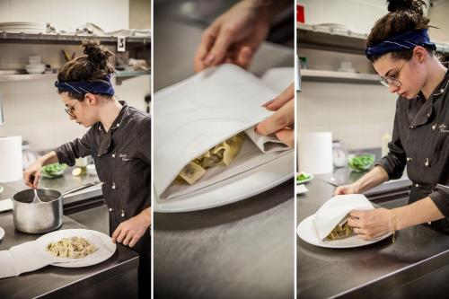 a chef preparing food in a kitchen and a plate of food at Hotel Palio in Asti