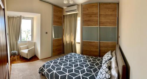 a bedroom with a bed and a chair and a window at Modern 2 bed room large apartment in Nicosia