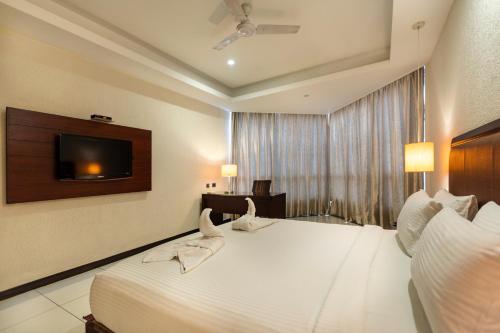 a hotel room with a white bed and a television at The Bentley Seaside Boutique Hotel in Chennai
