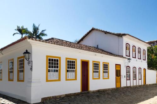 ein weißes Gebäude mit gelben Türen und Fenstern in der Unterkunft Pousada do Ouro in Paraty
