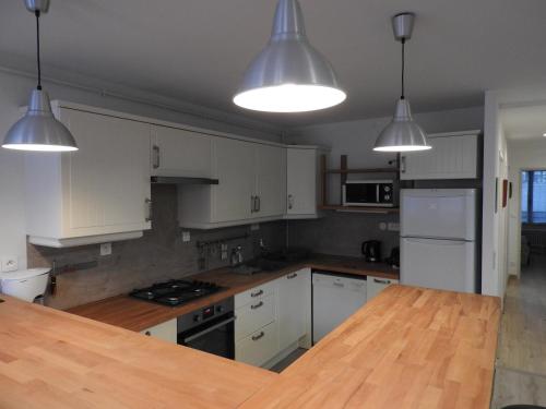 a kitchen with white cabinets and a wooden counter top at Appartement hyper centre ville au calme in Besançon