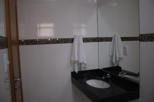 a bathroom with a sink and a mirror at Ouro Minas Plaza Hotel in Aparecida