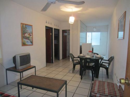 a living room with a tv and a table with chairs at Hotel Vagabundo Puerto Vallarta in Puerto Vallarta