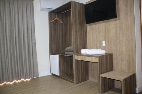 a room with a tv and a bench in a room at Ouro Minas Plaza Hotel in Aparecida