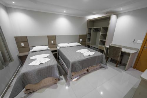 two beds in a small room with a kitchen at Prudentópolis Palace Hotel in Prudentópolis
