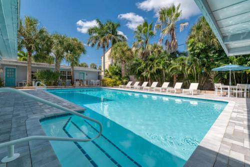 a large swimming pool with chairs and umbrellas at Mulberry Cottage in Siesta Key