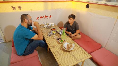 two men sitting at a table in a tent at Negev Camel Ranch in Dimona