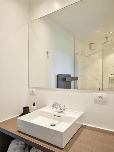 a white bathroom with a sink and a mirror at Boutique Hotel Ter Wallen in Izegem