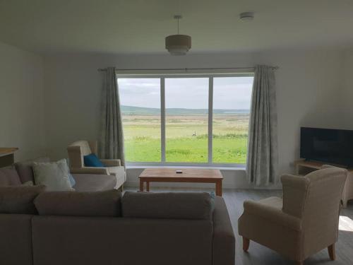 a living room with a couch and chairs and a large window at Cottiscarth Cottages in Finstown