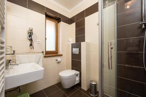 a bathroom with a toilet and a sink and a shower at Horský Hotel Kristína in Hruštín