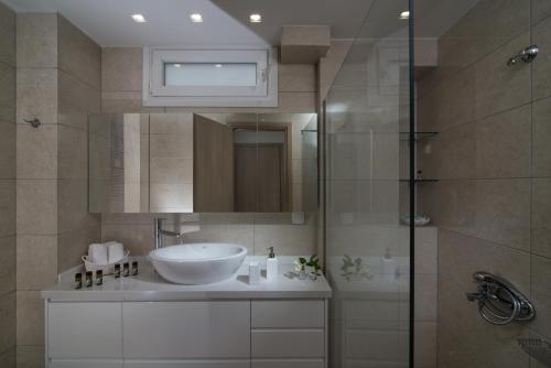 La salle de bains est pourvue d'un lavabo et d'une douche en verre. dans l'établissement Gras Houses - Near to sandy beach, à Agia Pelagia