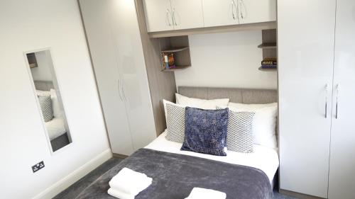 a small bedroom with a bed and white cabinets at The Hatton Rooms in New Bedfont