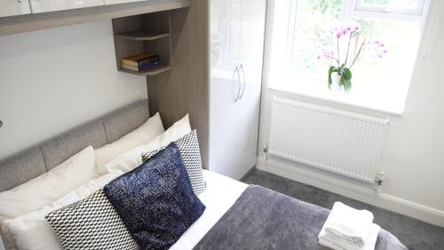 a bedroom with a bed with pillows and a window at The Hatton Rooms in New Bedfont
