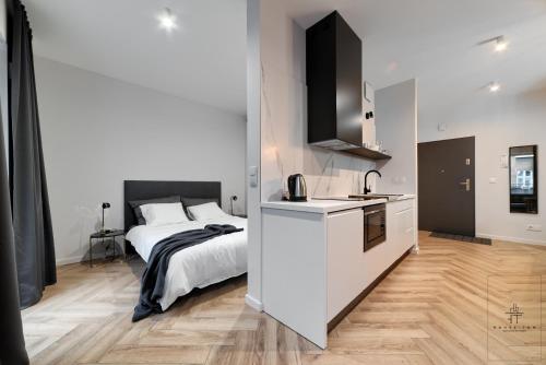 a white bedroom with a bed and a kitchen at Apartament Business in Poznań