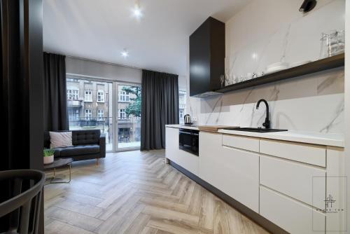 Una cocina con gabinetes blancos y una sala de estar. en Apartament Business, en Poznan
