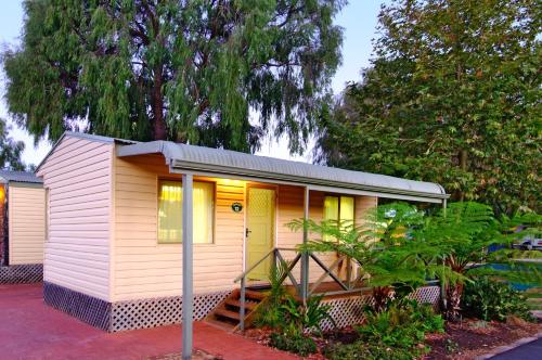 a small yellow house with a porch and trees at BIG4 Breeze Holiday Parks - Busselton in Busselton