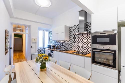 a kitchen with a table with a vase of flowers on it at Faro Guest House in Faro